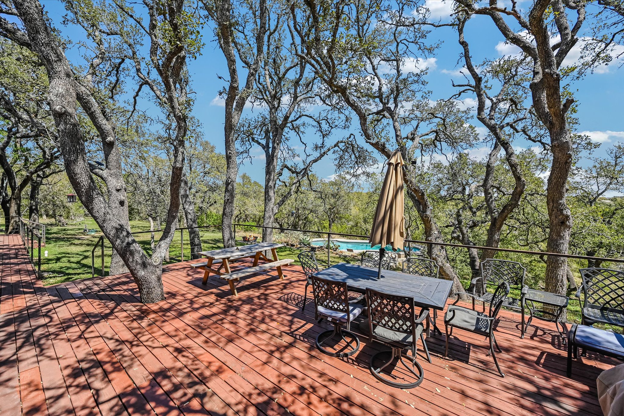 411 Whitetail Ridge Austin, TX 78737 - Photo 21 of 38 Wooden deck with outdoor dining space, view of wooded area, and an outdoor pool