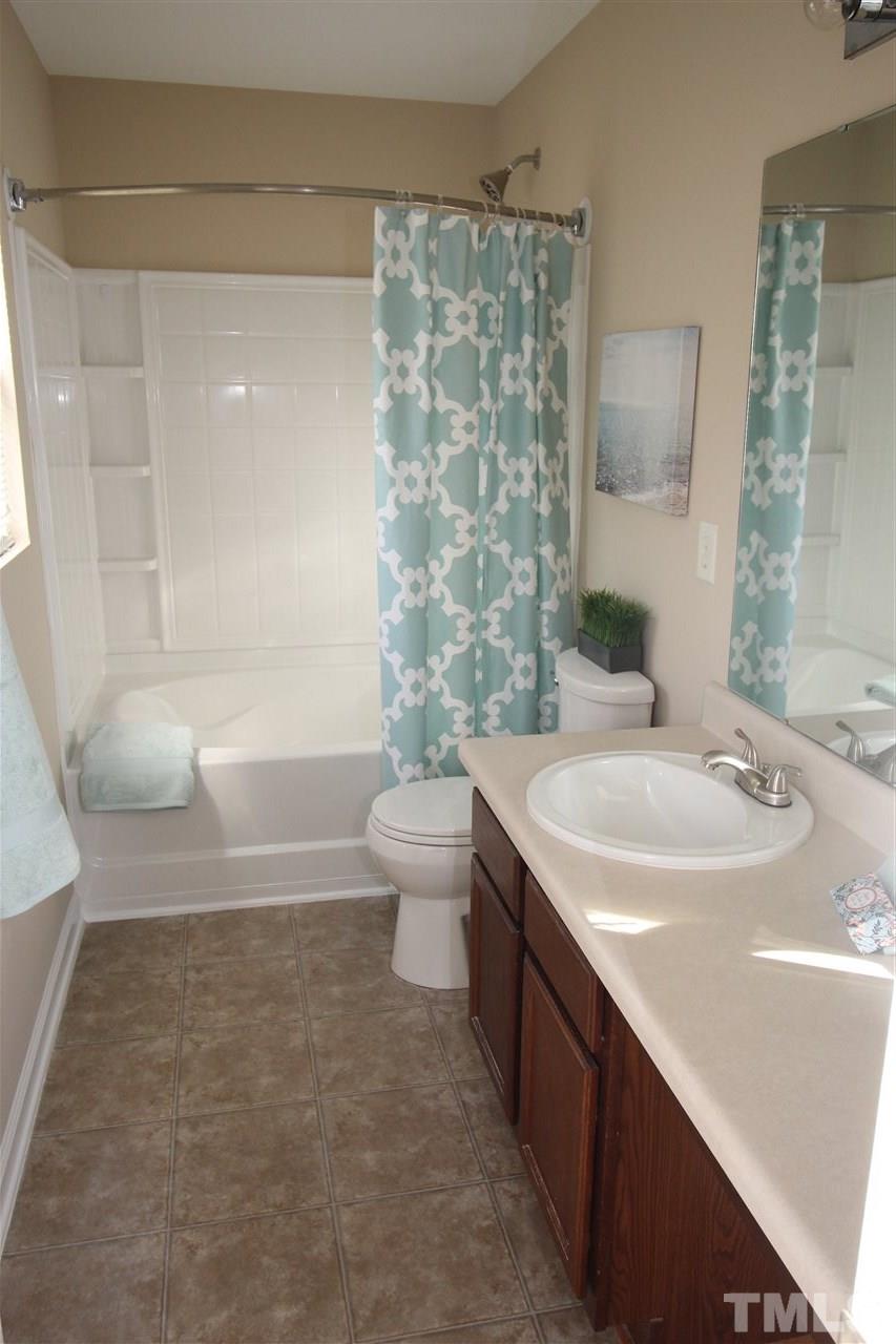 2411 Quarry Ridge Lane Raleigh, NC 27610 - Photo 15 of 22 a bathroom with a granite countertop sink a toilet a mirror and bathtub