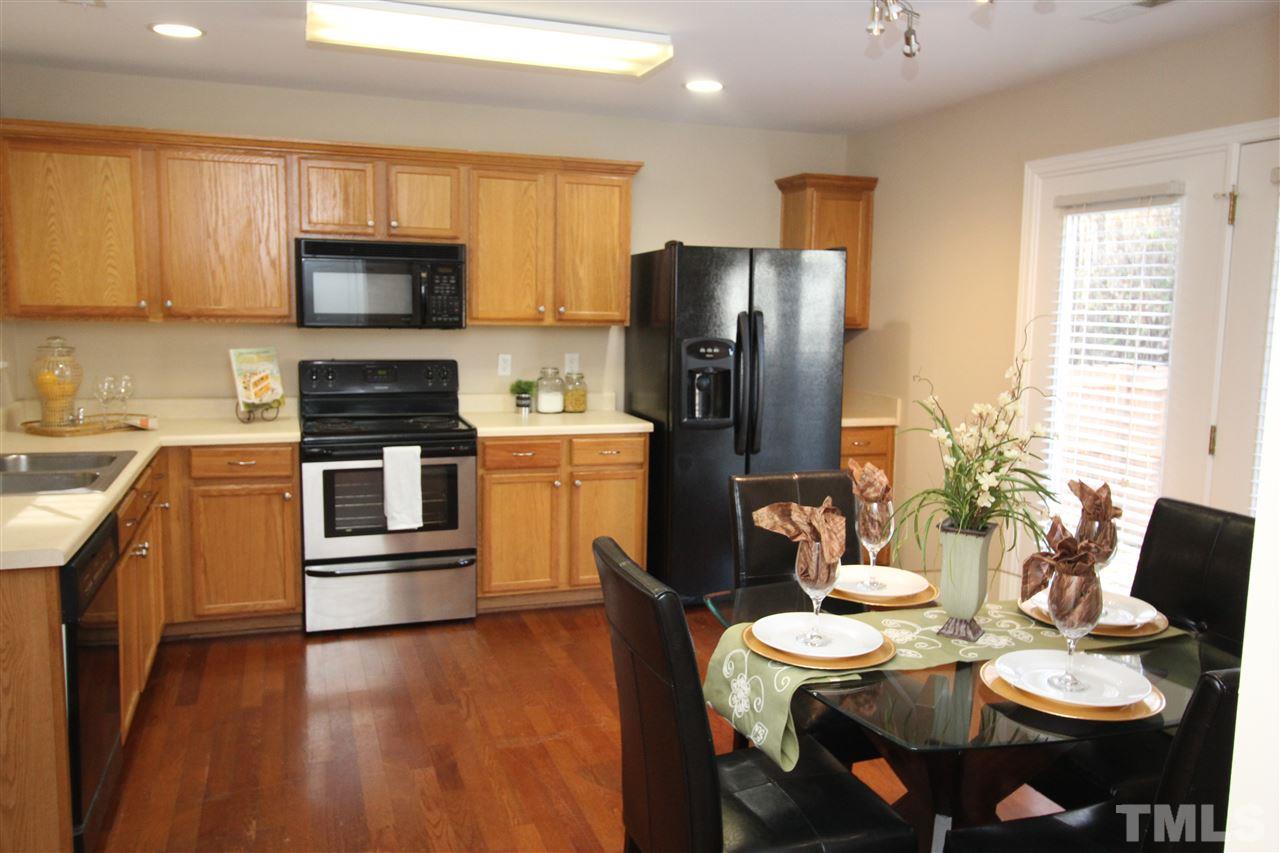 2411 Quarry Ridge Lane Raleigh, NC 27610 - Photo 8 of 22 a kitchen with stainless steel appliances kitchen island granite countertop a refrigerator a stove top oven a sink dishwasher and a dining table with wooden floor