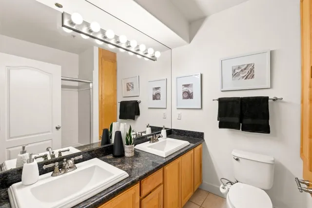 a bathroom with a granite countertop sink mirror vanity and toilet