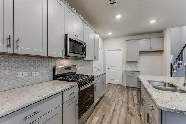 a kitchen with granite countertop a sink a counter space stainless steel appliances and cabinets