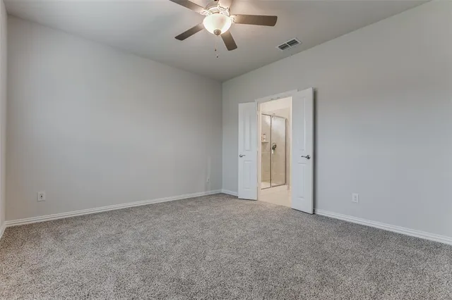 an empty room with chandelier fan and windows