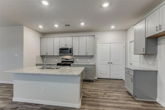 a kitchen with kitchen island granite countertop a sink stainless steel appliances and cabinets