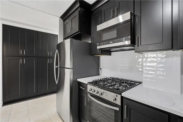 a kitchen with stainless steel appliances granite countertop a refrigerator and a stove top oven