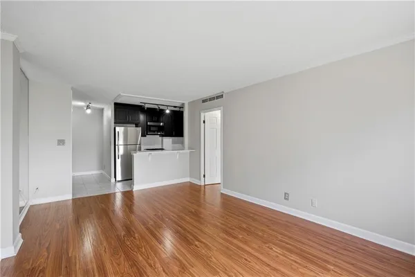 a view of an empty room with wooden floor and a window