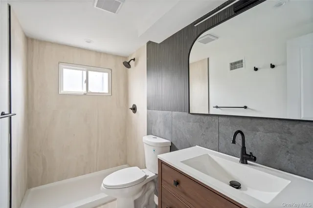 a bathroom with a sink a toilet and shower