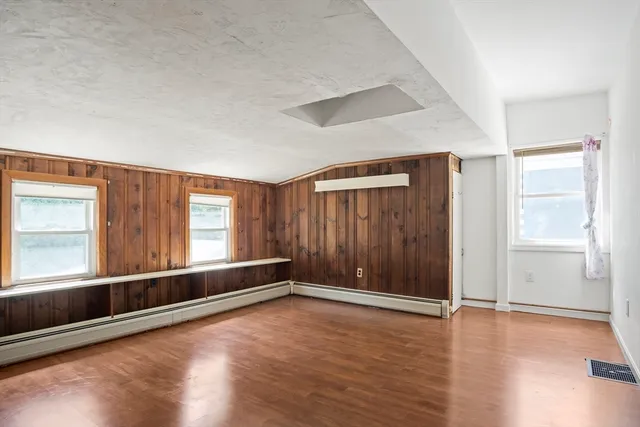an empty room with wooden floor and windows with curtains