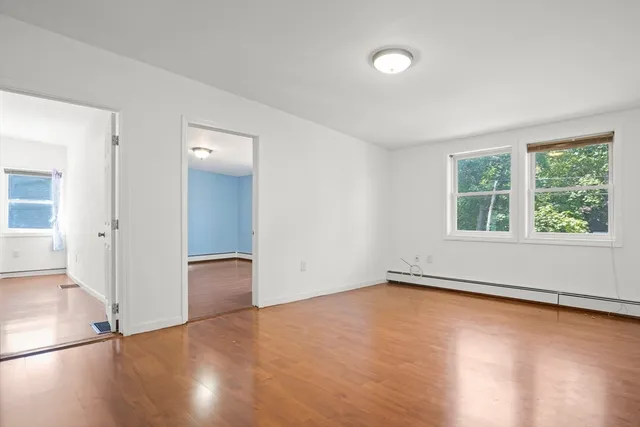 an empty room with wooden floor and windows
