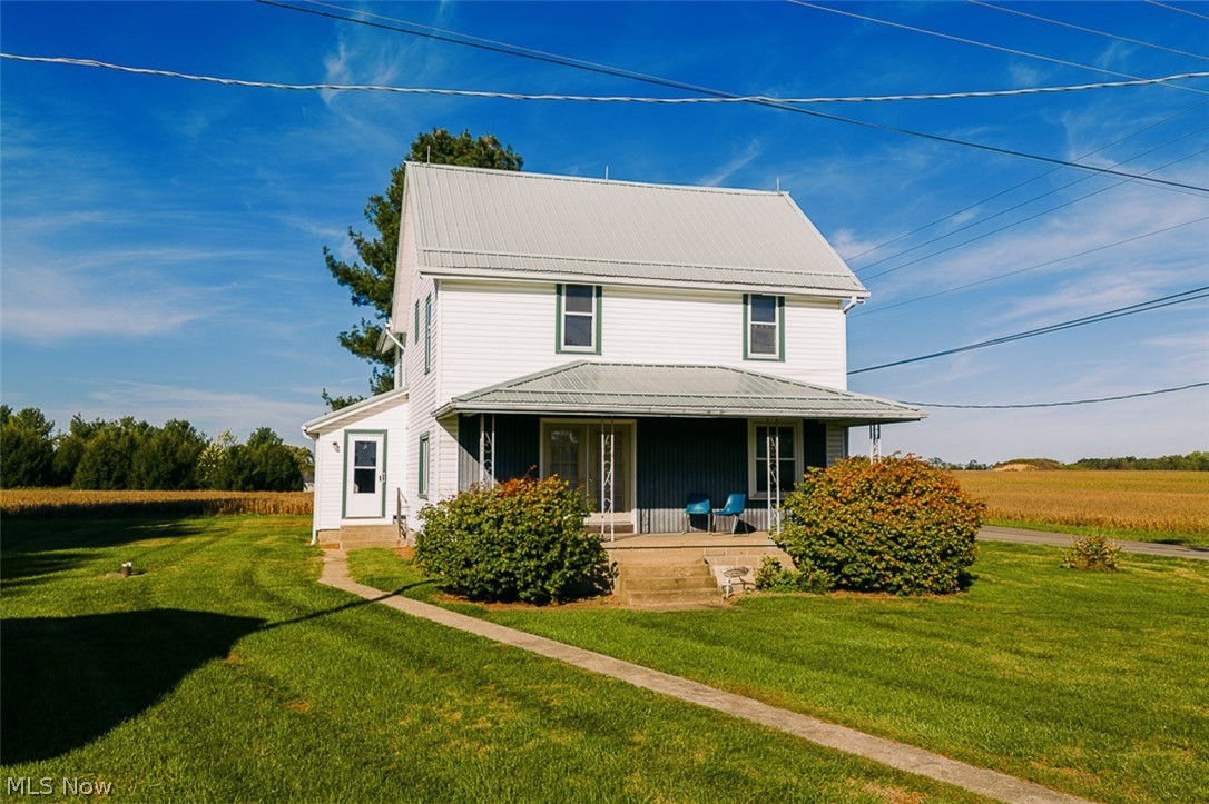 Front view of property featuring covered porch and a yard