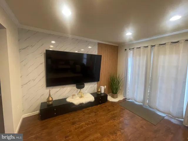 a living room with a bed furniture and a flat screen tv