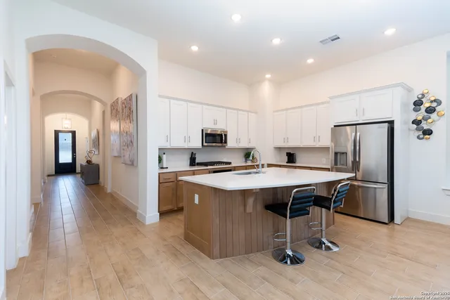 a kitchen with stainless steel appliances granite countertop a table chairs sink refrigerator and cabinets