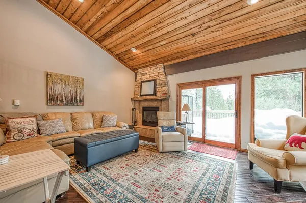 a living room with furniture large windows and wooden floor