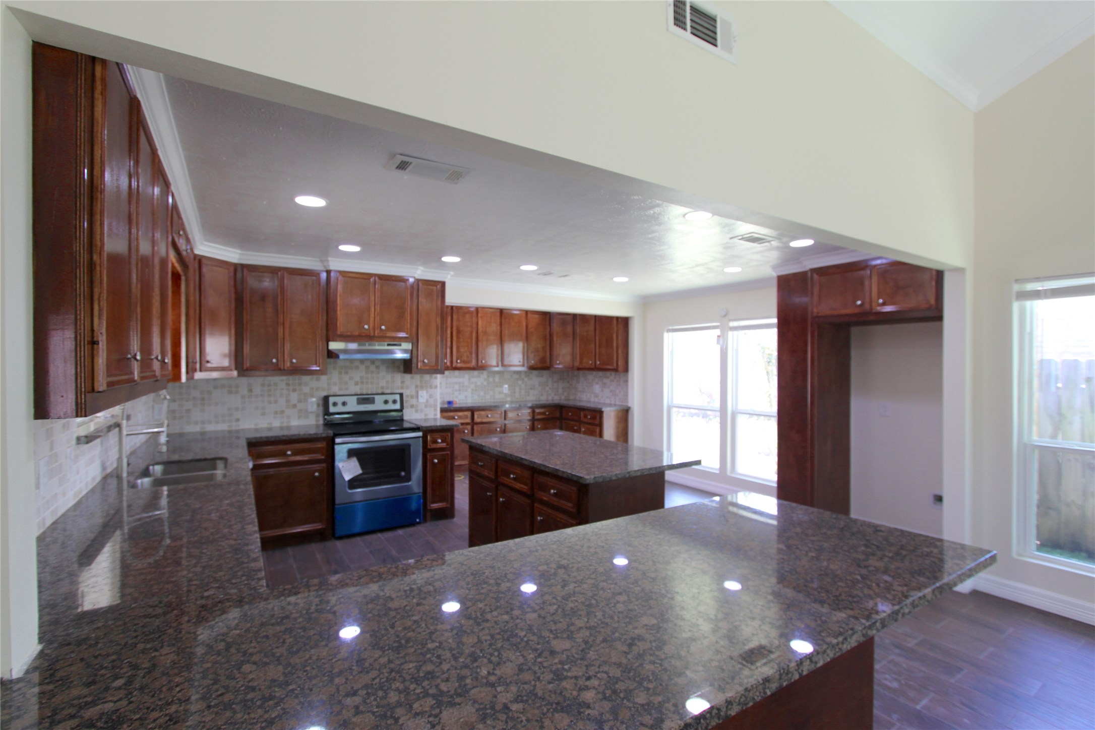 4330 Regency Villa Drive Houston, TX 77084 - Photo 1 of 13 a open kitchen with kitchen island a stove a sink a refrigerator cabinets and wooden floor