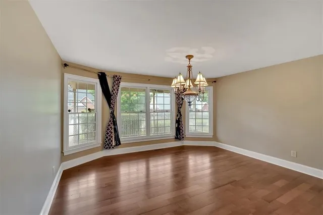 an empty room with windows and chandelier fan