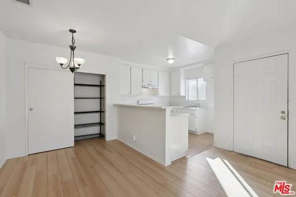 a kitchen with wooden floors and white cabinets