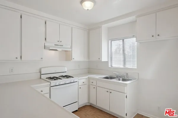 a kitchen with cabinets appliances a sink and a window