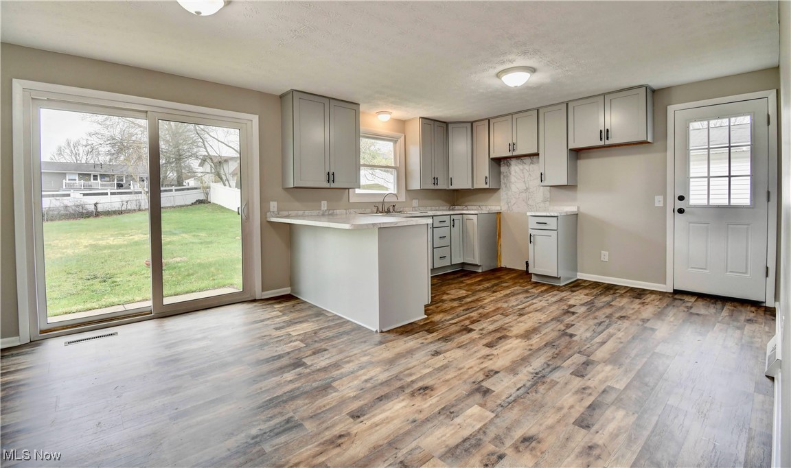 494 Moore Road Akron, OH 44319 - Photo 6 of 30 Kitchen featuring a peninsula, visible vents, wood finished floors, and gray cabinets