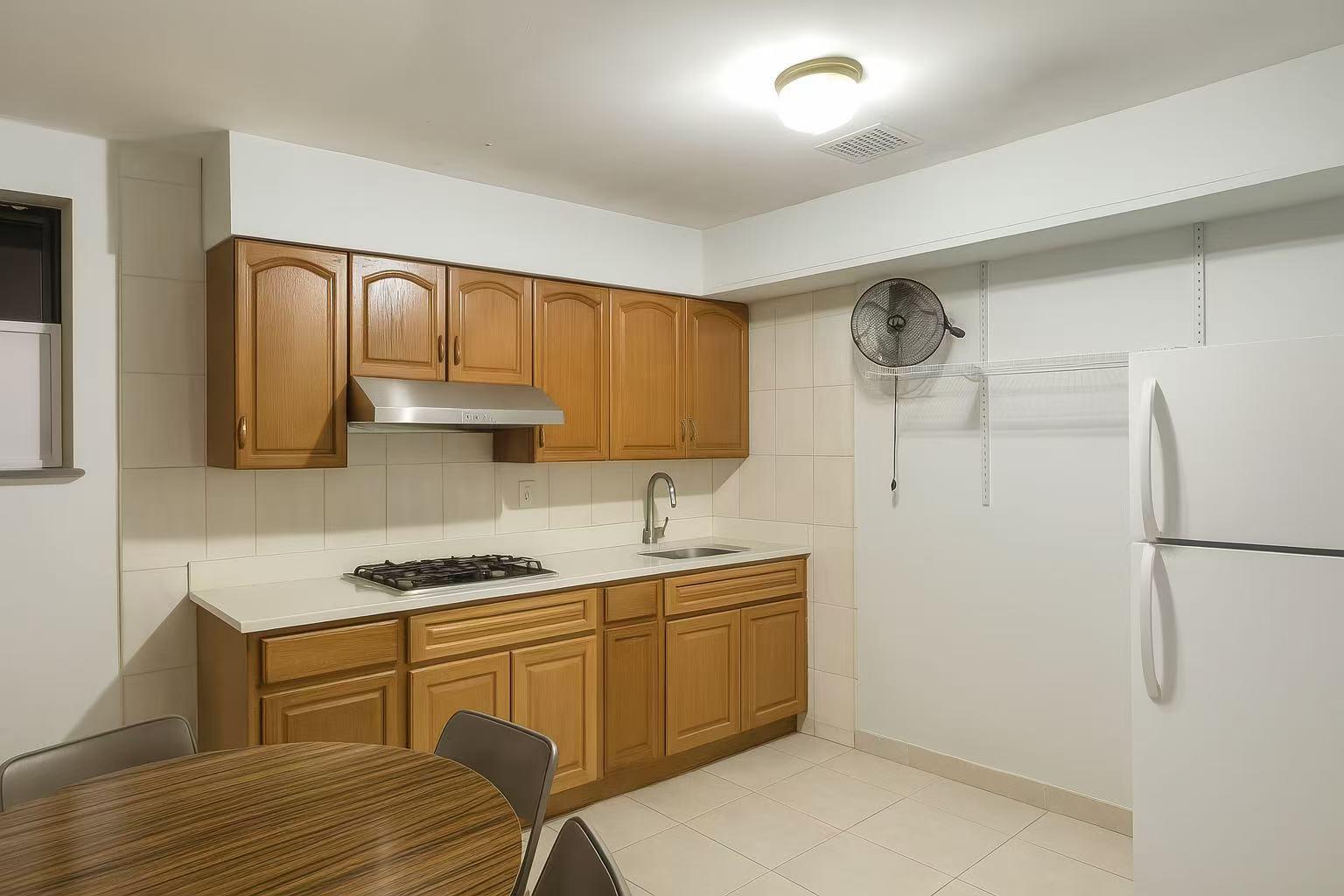 108-11 44th Avenue Queens, NY 11368 - Photo 4 of 11 a kitchen with a refrigerator a sink and cabinets