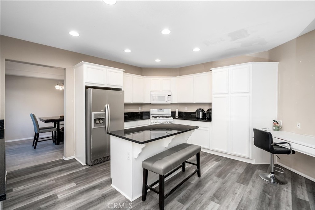 37867 Shady Maple Road Murrieta, CA 92563 - Photo 9 of 68 a kitchen with a refrigerator a stove and a dining table with wooden floor
