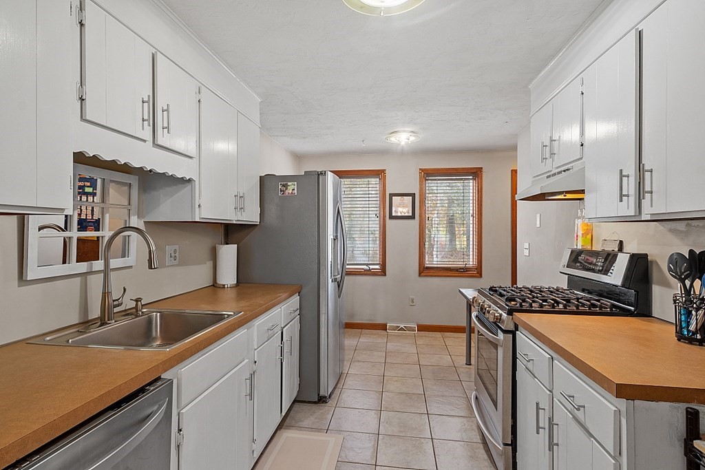 403 Cardinal Lane, Unit 403 Tyngsborough, MA 01879 - Photo 11 of 27 a kitchen with stainless steel appliances granite countertop a sink stove and refrigerator