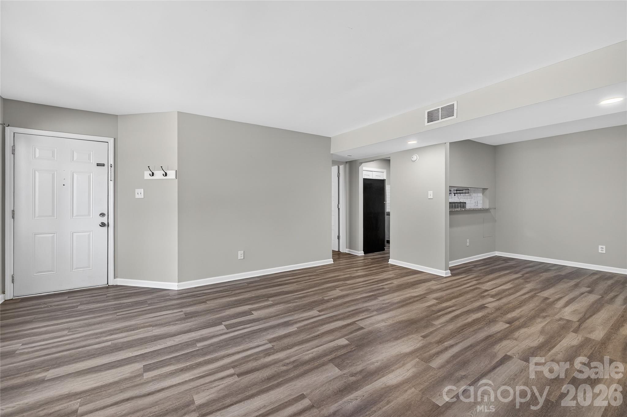 1612 Sharon Road West, Unit 67 Charlotte, NC 28210 - Photo 5 of 19 a view of an empty room with wooden floor and kitchen space