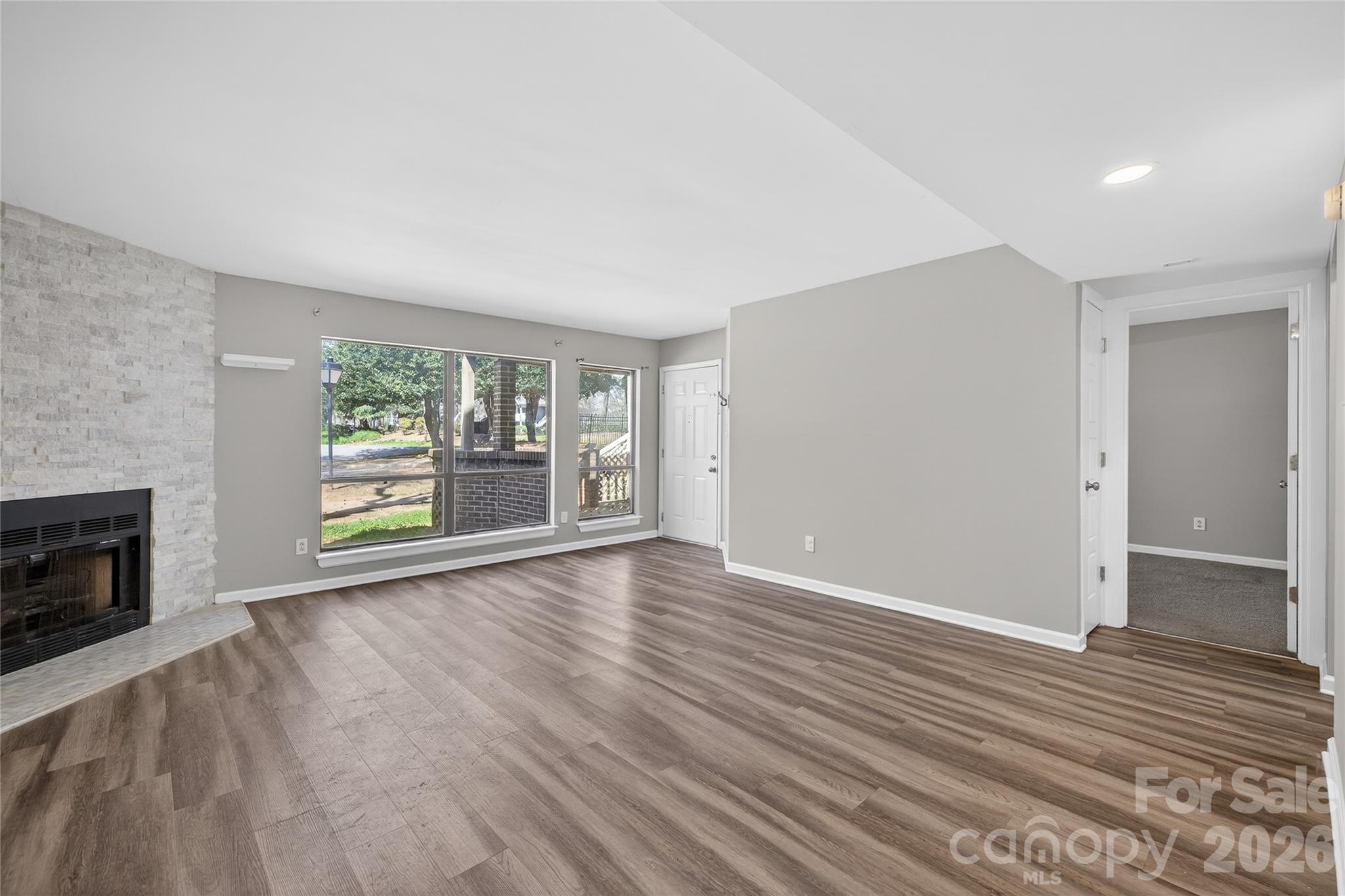 1612 Sharon Road West, Unit 67 Charlotte, NC 28210 - Photo 6 of 19 an empty room with wooden floor fireplace and windows