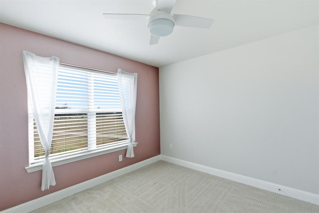 4600 Old Brock Road Weatherford, TX 76087 - Photo 30 of 37 Room featuring a window with white blinds and sheer curtains, a ceiling fan with integrated lighting, textured pink accent wall, white baseboards, and light-toned carpet flooring