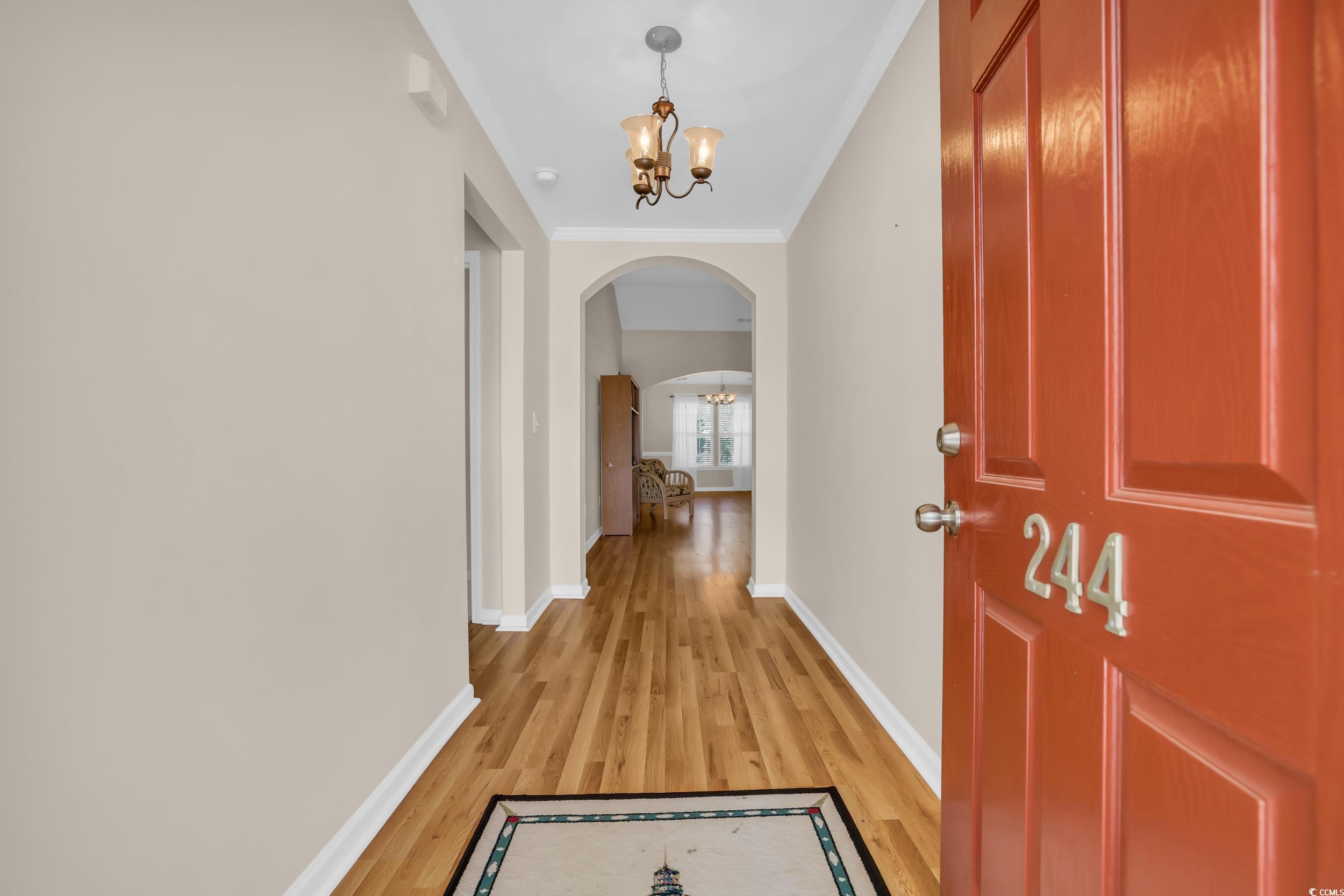 Hallway with an inviting chandelier, crown molding