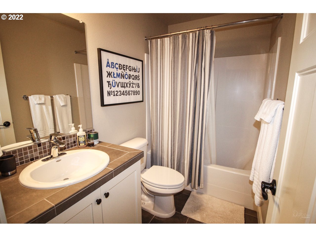 14174 Southwest Compass Drive Beaverton, OR 97005 - Photo 5 of 32 a bathroom with a sink a toilet a mirror and shower curtain