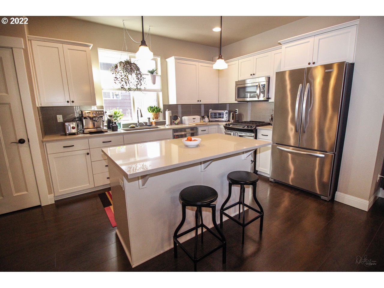 14174 Southwest Compass Drive Beaverton, OR 97005 - Photo 8 of 32 a kitchen with stainless steel appliances granite countertop a refrigerator a sink dishwasher a stove and white cabinets with wooden floor