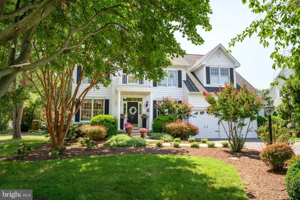 a front view of a house with a garden and trees