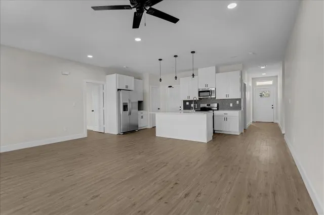 a view of empty room with wooden floor and fan