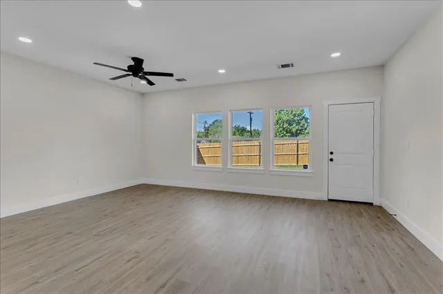a view of empty room with wooden floor and fan
