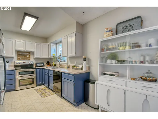 a kitchen with stainless steel appliances kitchen island granite countertop a refrigerator a sink dishwasher and white cabinets with wooden floor