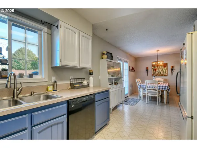 a kitchen with stainless steel appliances granite countertop sink window dining table and chairs
