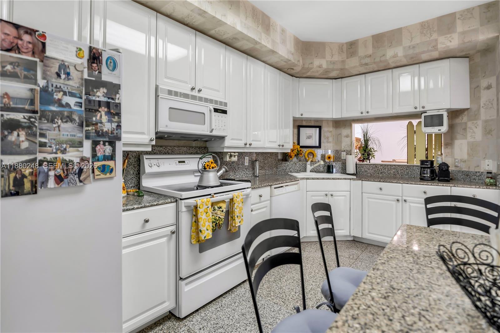 888 Brickell Key Drive, Unit 1807 Miami, FL 33131 - Photo 15 of 58 a kitchen with stainless steel appliances granite countertop a stove a sink dishwasher and white cabinets with wooden floor
