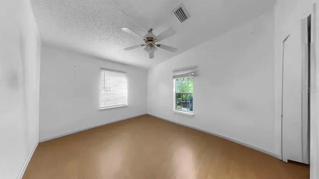 an empty room with a window and a fan