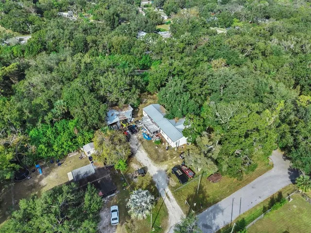 an aerial view of residential house with outdoor space and trees all around