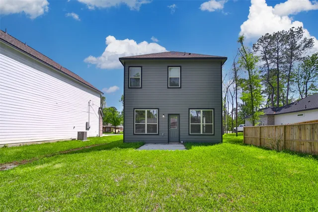 a view of a house with a yard and a large tree