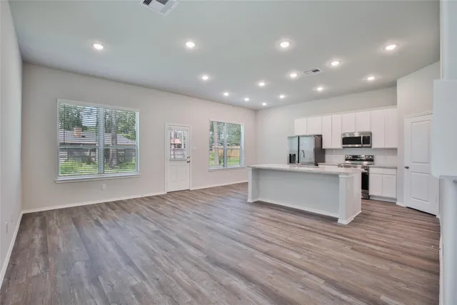 a large kitchen with stainless steel appliances a large counter top and a wooden floors
