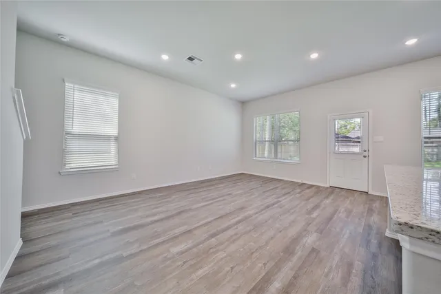 an empty room with wooden floor and windows