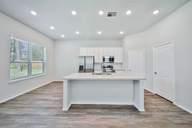 a view of kitchen with stainless steel appliances granite countertop cabinets and wooden floor