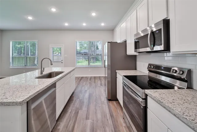 a kitchen with stainless steel appliances granite countertop a sink stove and microwave