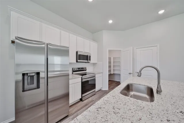a kitchen with granite countertop a sink stainless steel appliances and cabinets