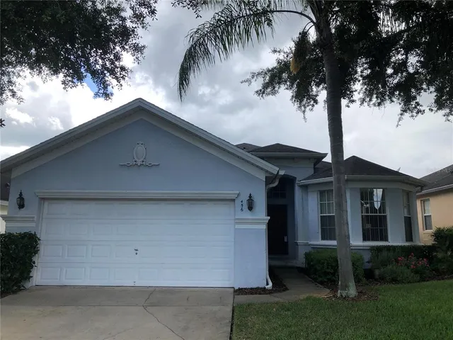 front view of house with a yard and palm trees