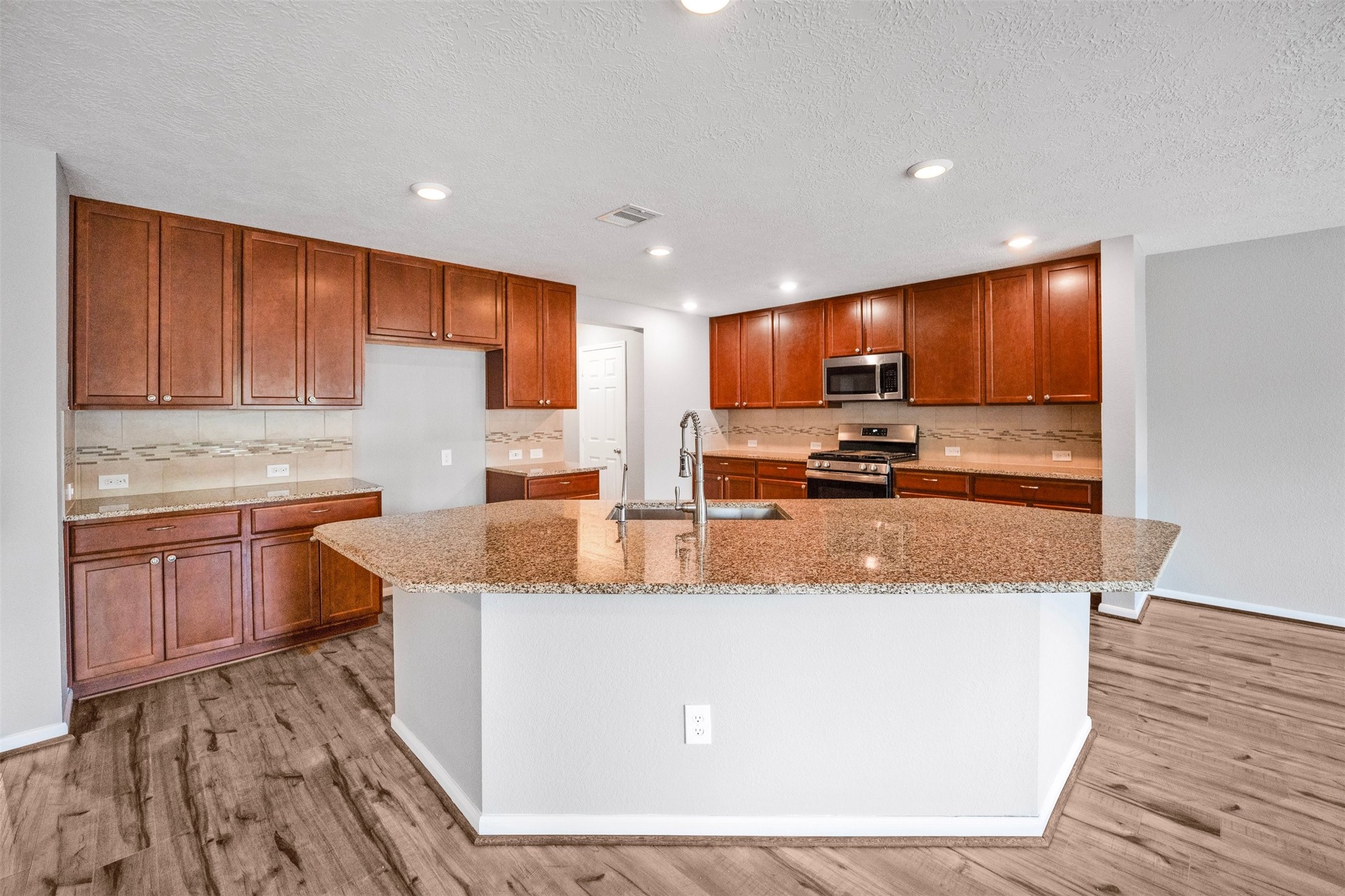 1107 Epworth Ct. Conroe, TX 77304 - Photo 12 of 38 a kitchen with kitchen island granite countertop wooden cabinets a sink and appliances