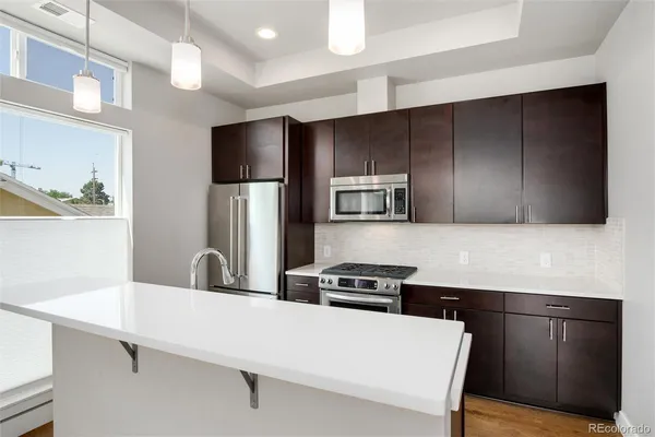 a kitchen with stainless steel appliances a sink a stove a microwave a refrigerator and cabinets