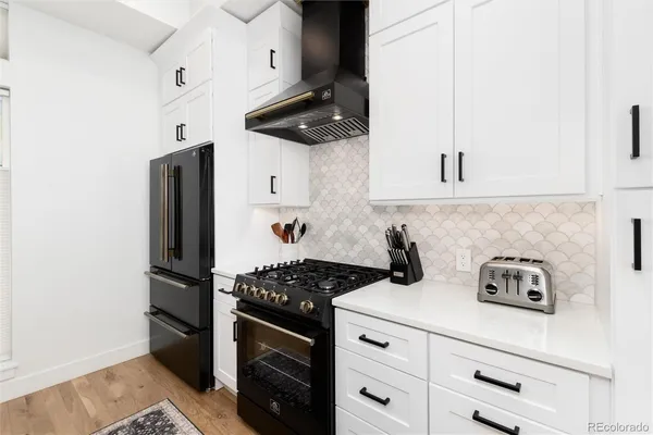 a kitchen with stainless steel appliances a refrigerator stove and white cabinets