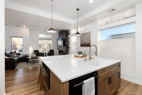 a kitchen with a stove a sink a kitchen island with wooden cabinets and couches