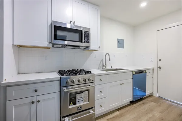 a kitchen with stainless steel appliances a stove microwave and sink